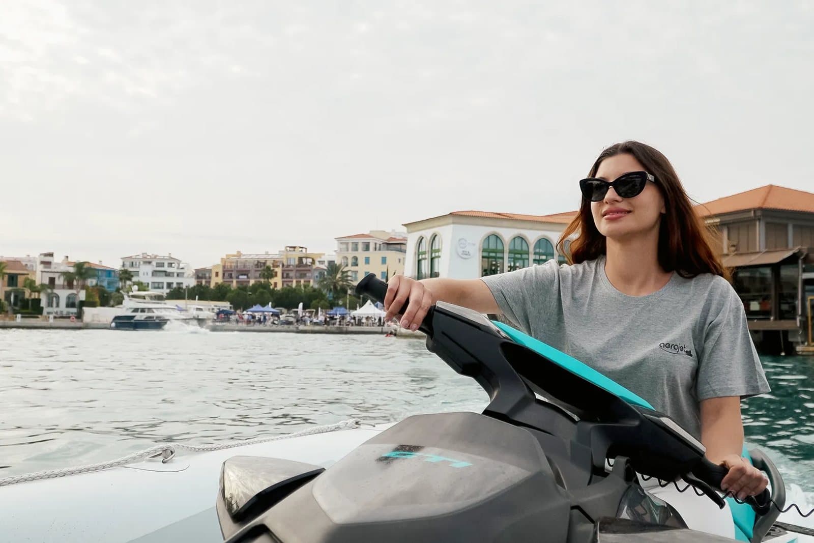 Επιβάτισσα στη θέση του jet ski, με τη μαρίνα στο βάθος
