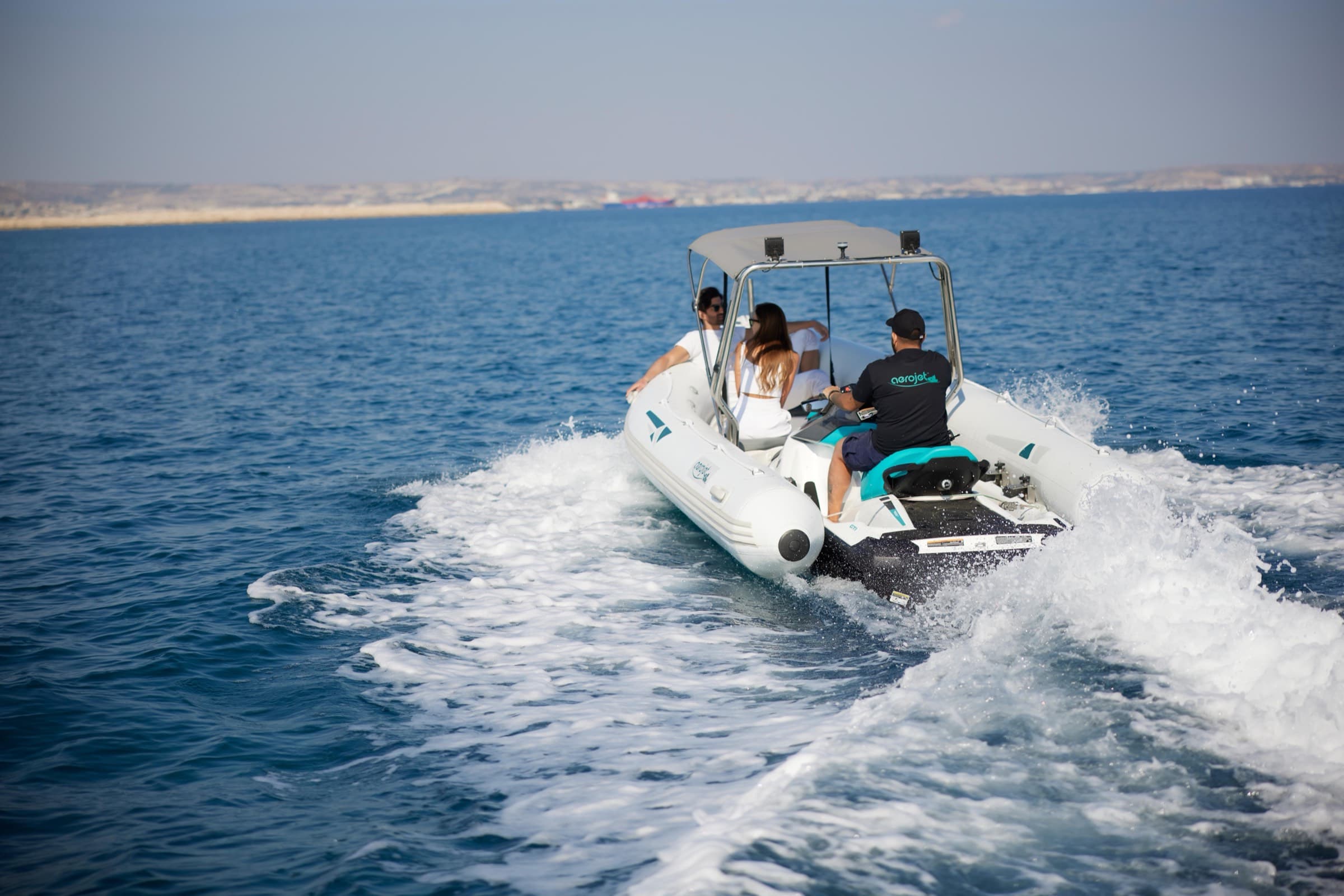Το Aerojet από πίσω σε πλεύση: ο οδηγός στο jet ski στην πρύμνη, δύο επιβάτες μπροστά, με απόνερα