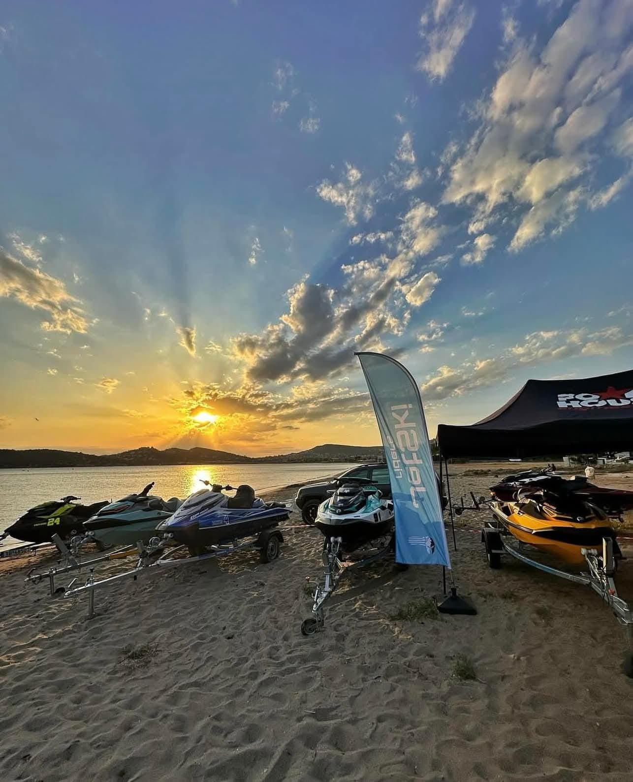 Ηλιοβασίλεμα σε παραλία: jet ski πάνω στα τρέιλερ και η σημαία Jetski Riders