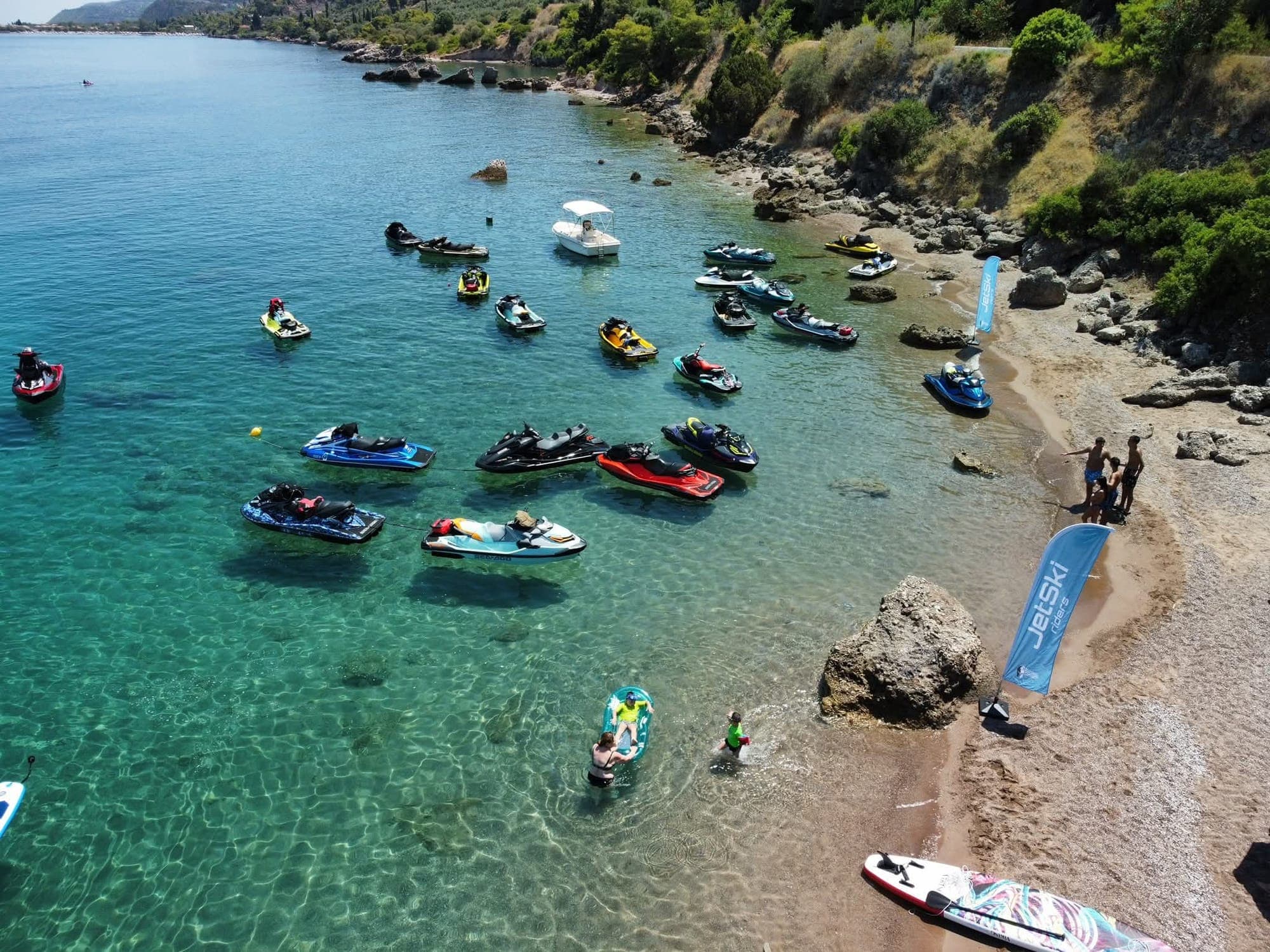Από ψηλά: jet ski αγκυροβολημένα σε κόλπο και η σημαία Jetski Riders στην παραλία