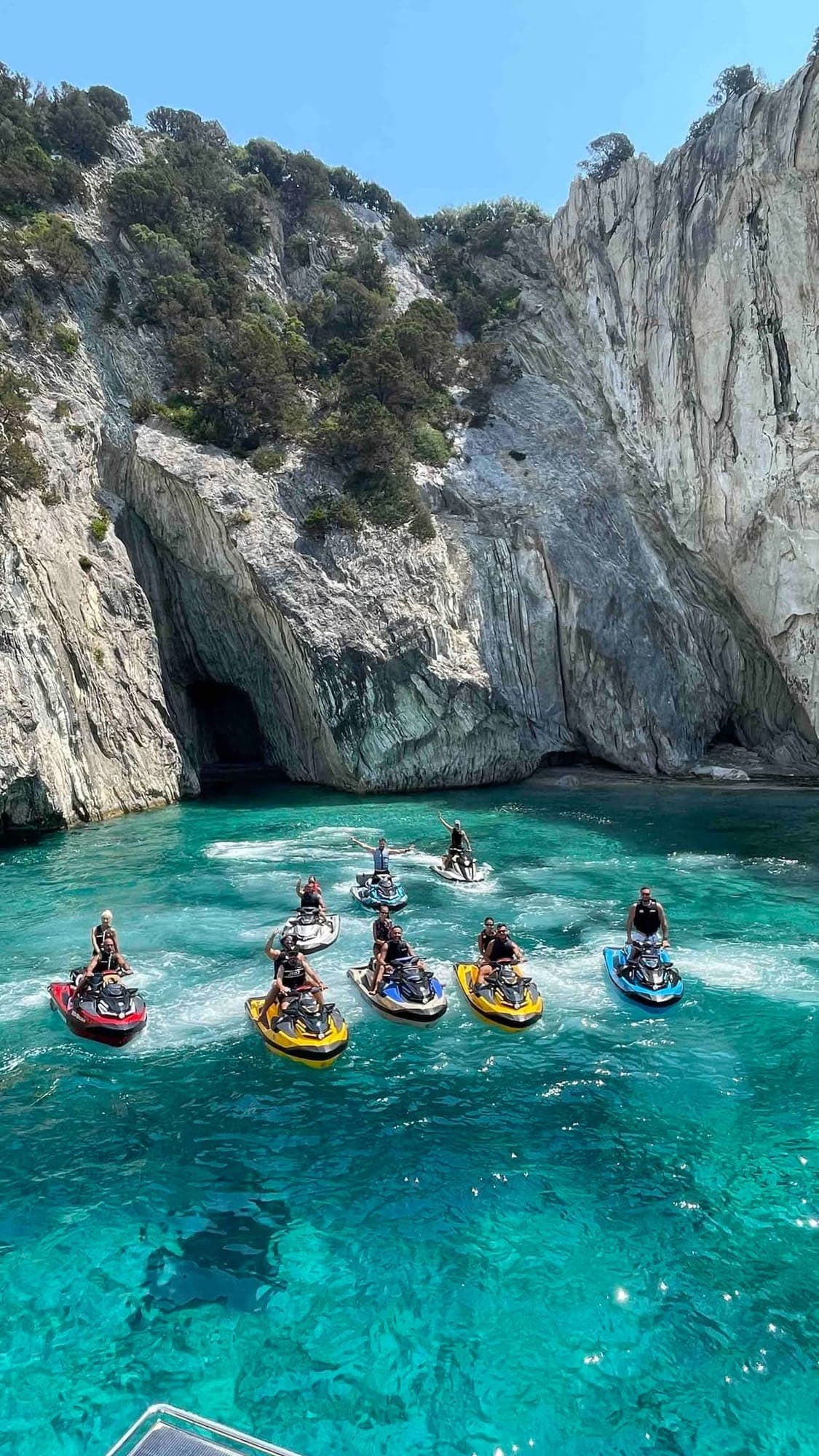 Η παρέα με τα jet ski σε τιρκουάζ νερά, μπροστά σε λευκά βράχια και μια σπηλιά